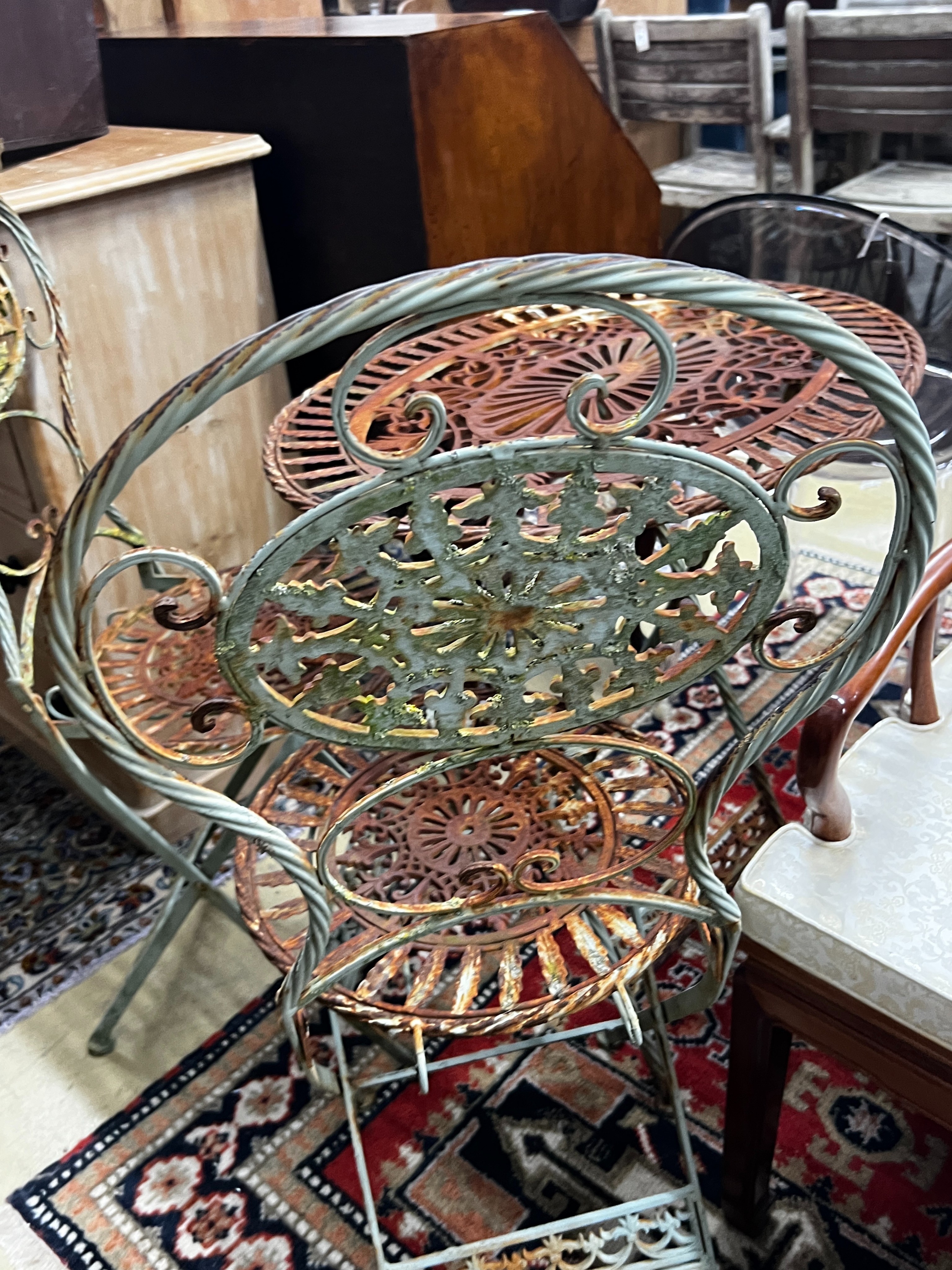 A painted oval folding wrought iron garden table, length 71cm, width 54cm, height 75cm together with two matching chairs